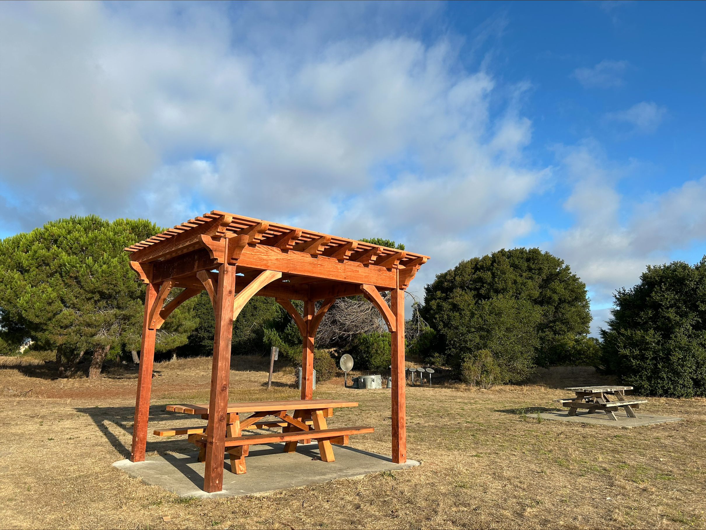 new redwood picnic tables and shade ramada in a field at Candlestick